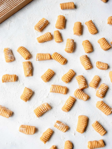 pieces of cut and floured sweet potato gnocci set out on a floured surface
