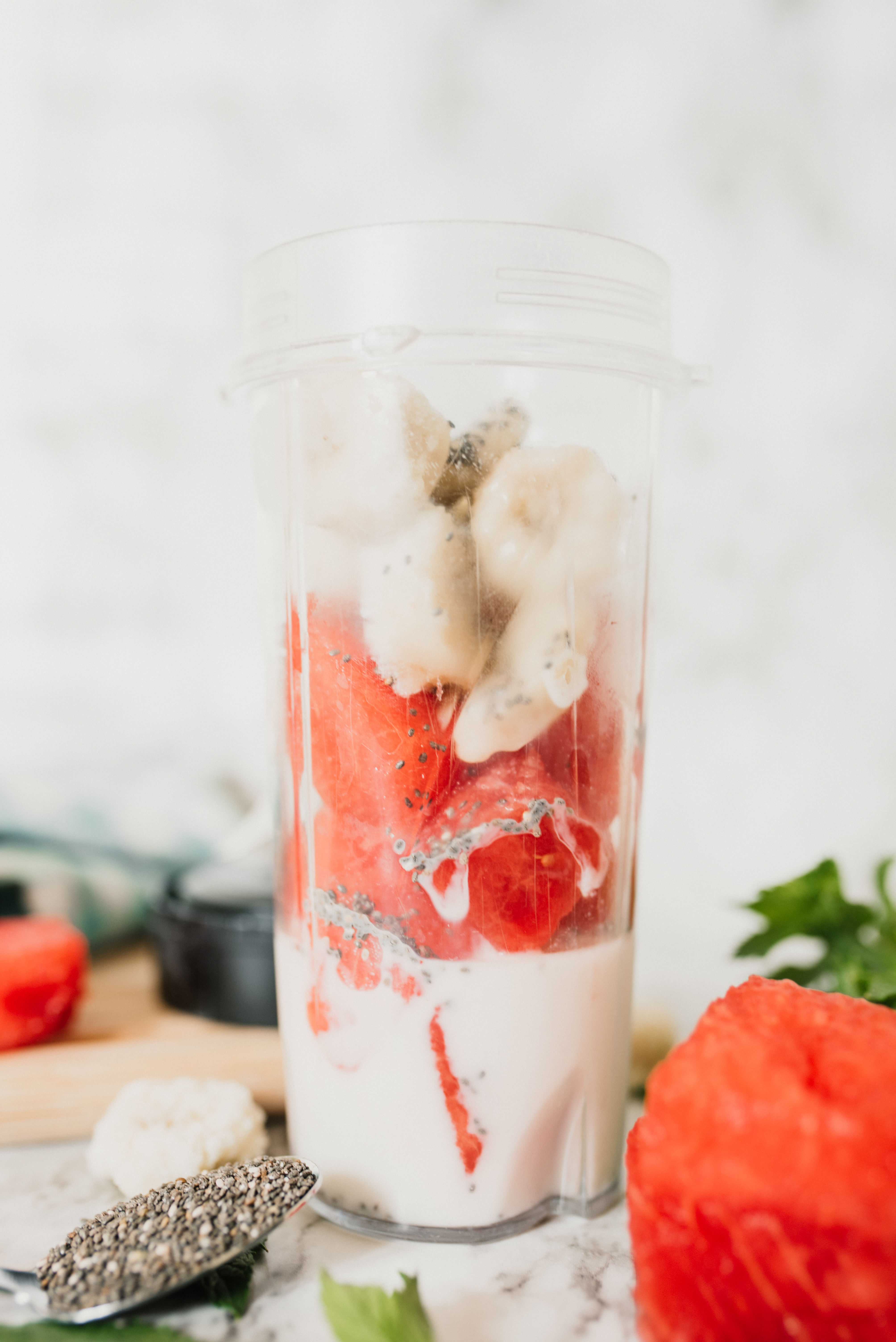 a small smoothie cup filled with almond milk, watermelon, chia seeds and frozen banana
