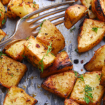 turkish potatoes on a parchment lined dish topped with fresh herbs and a silver fork