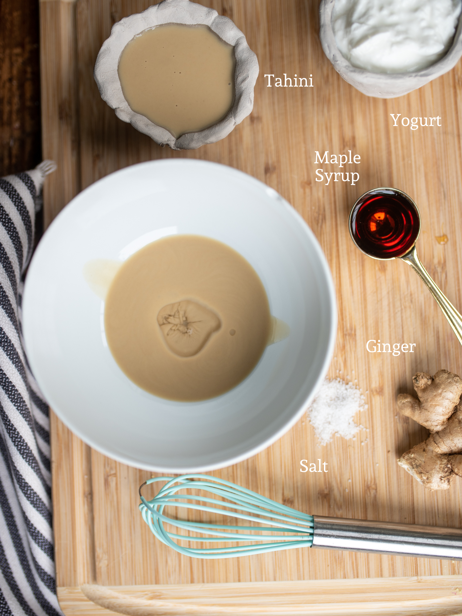 Ingredients for Low Acid Dresing laid out on a cutting board. There is yogurt, tahini, maple syrup, salt and ginger