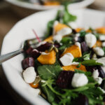 a white bowl of beetroot and butternut salad with a fork and a second salad behind it