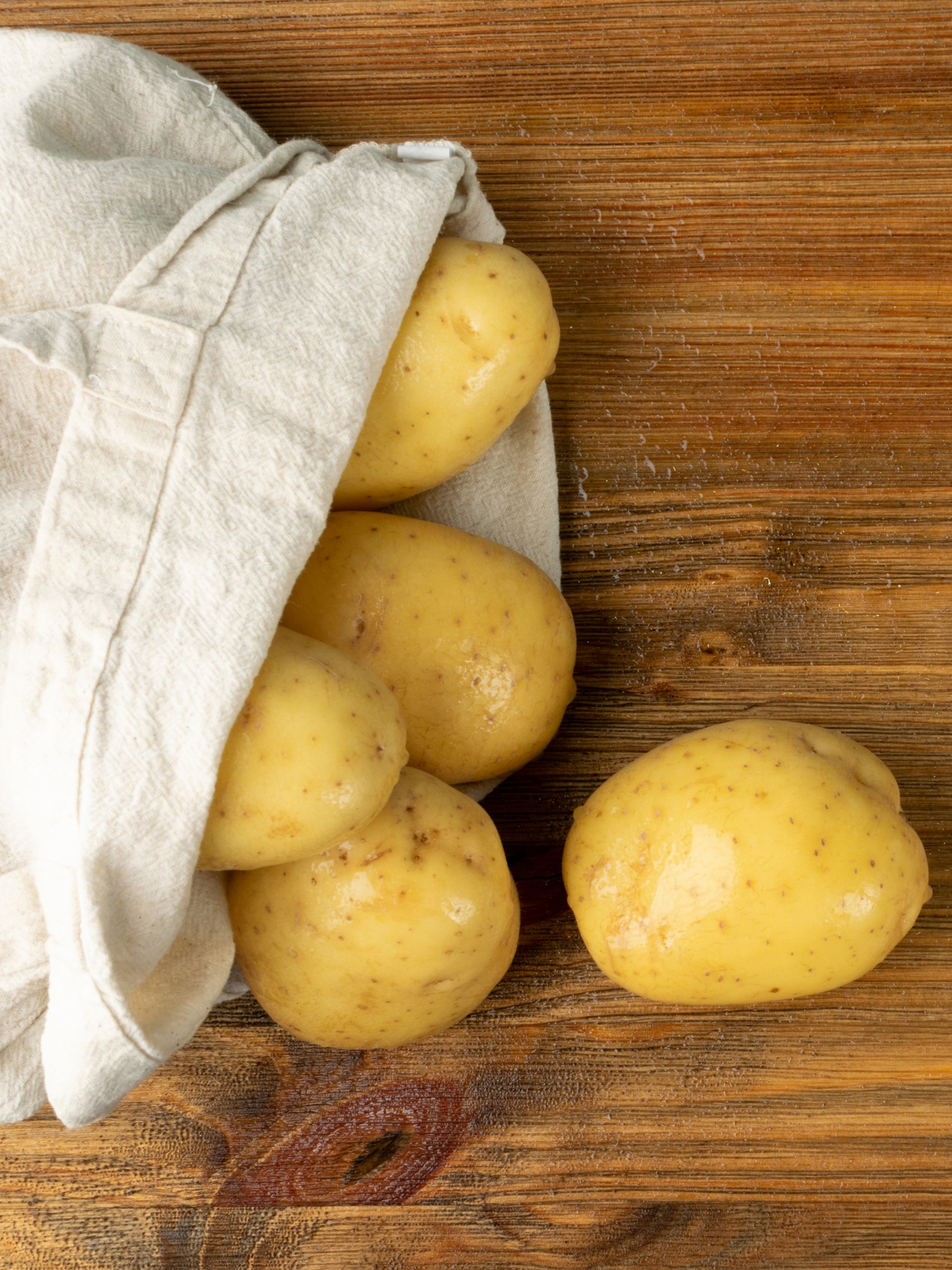 a cotton bag with potatoes spilling out onto a wooden table