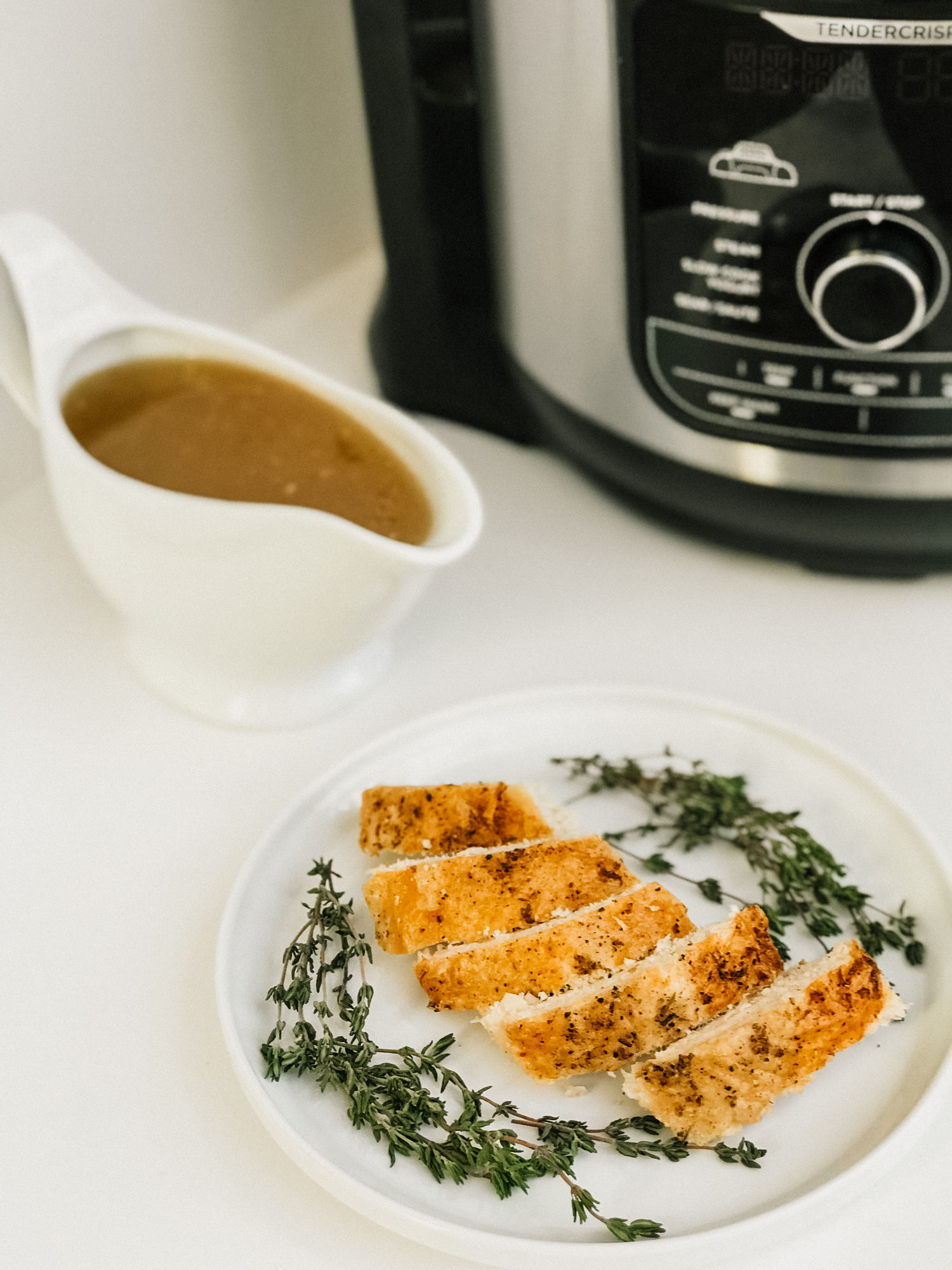 a plate of sliced herbed turkey breast with a pressure cooker and gluten free gravy in the background